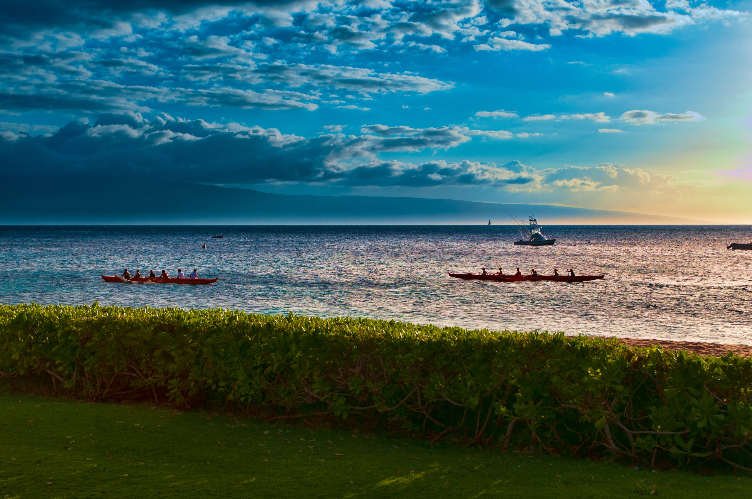 Two,Native,Hawaiian,Boats,Rowing,Past,At,Sunset,On,Maui,