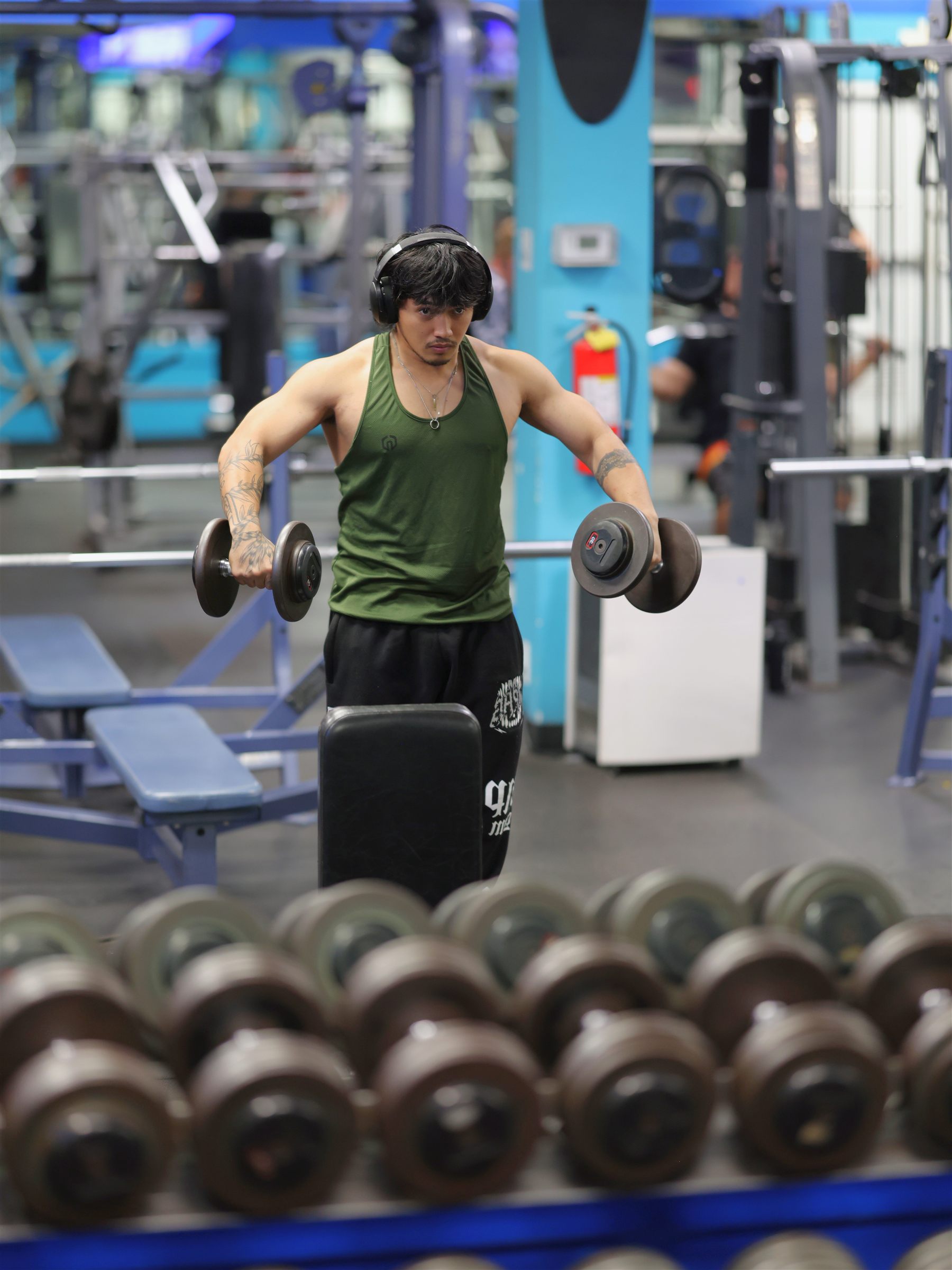 Member training with dumbbells beside the free-weight racks at Maui Powerhouse Gym