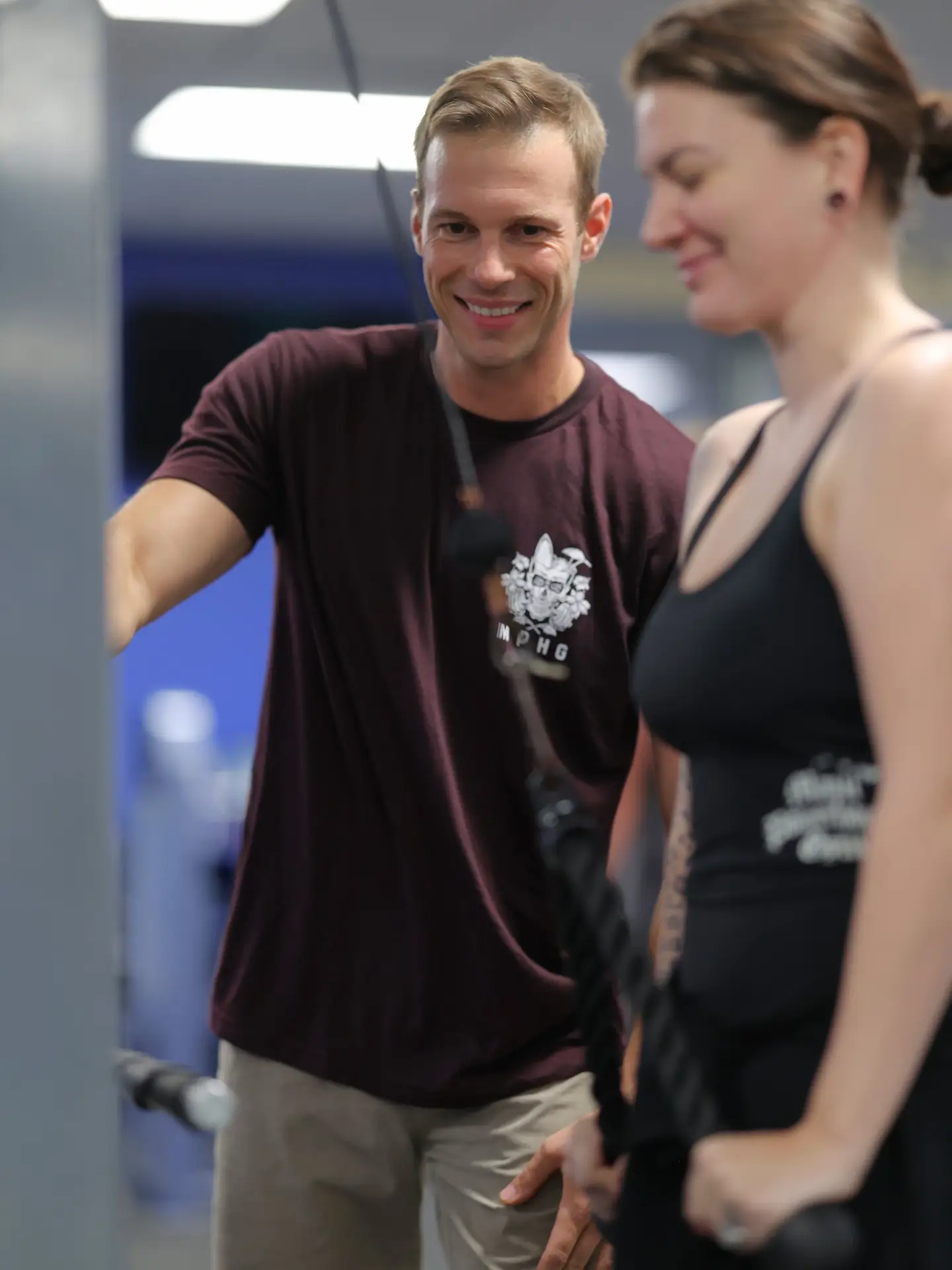 Maui Powerhouse Gym team member helping a woman beside gym equipment, easing gym intimidation for beginners