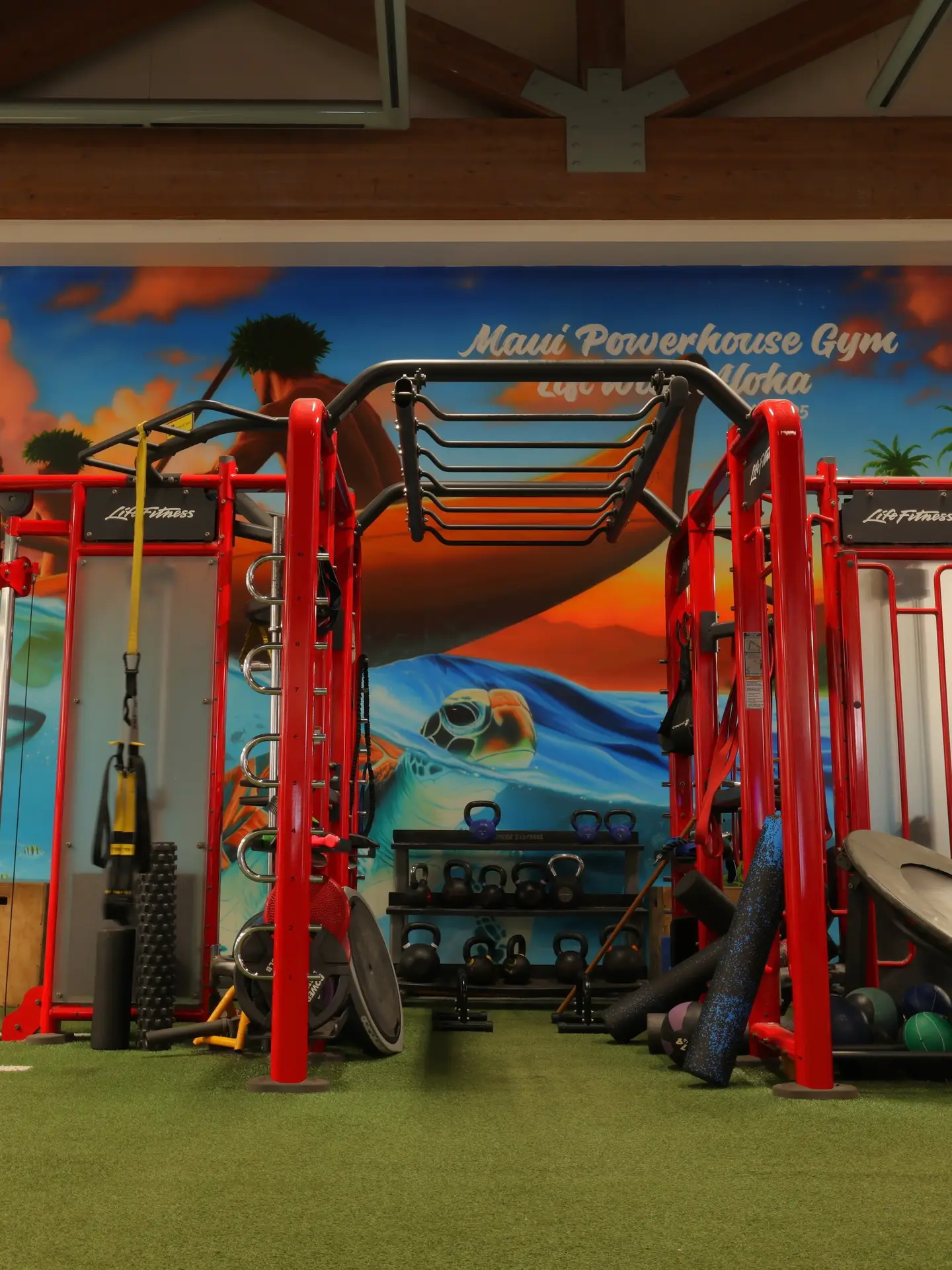 Maui Powerhouse Gym weight room with red equipment and a colorful Maui mural